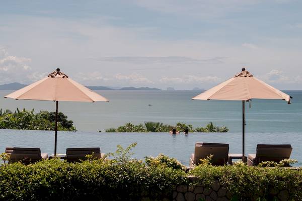 Poolansicht im Amatara Welleisure Resort mit zwei Sonnenschirmen und zwei Personen im Wasser.