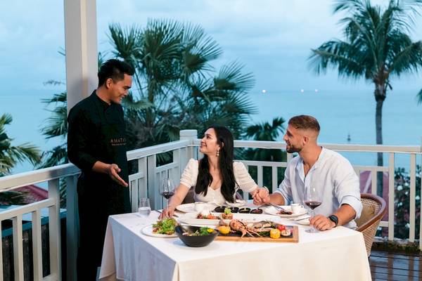 Ein Paar genießt ein Essen auf der Terrasse des Amatara Welleisure Resorts mit Blick auf das Meer.