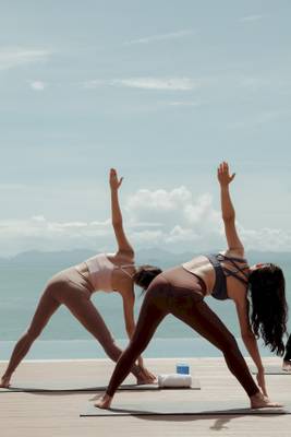 Frauen praktizieren Yoga am Strand mit Blick auf das Meer.