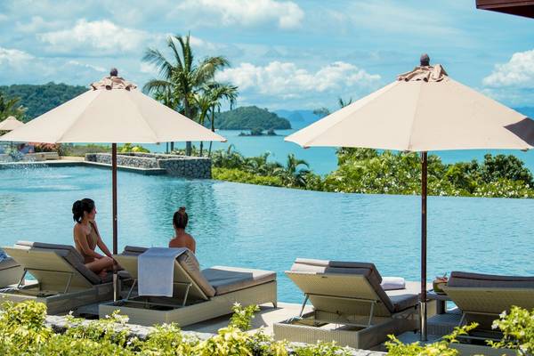 Zwei Frauen unter Sonnenschirmen am Poolbereich des Amatara Welleisure Resorts.