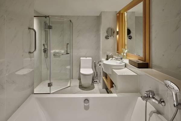Ein Badezimmer im Phuket Marriott Resort & Spa Merlin Beach mit einer Badewanne, einer Dusche, einem Waschbecken und einem Spiegel.