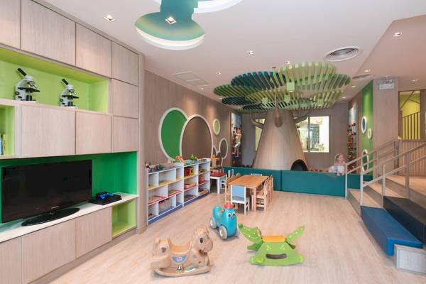 Kinderspielzimmer im Phuket Marriott Resort & Spa Merlin Beach mit Fernseher, Bücherregal, Spieltischen und Baum-Dekoration.