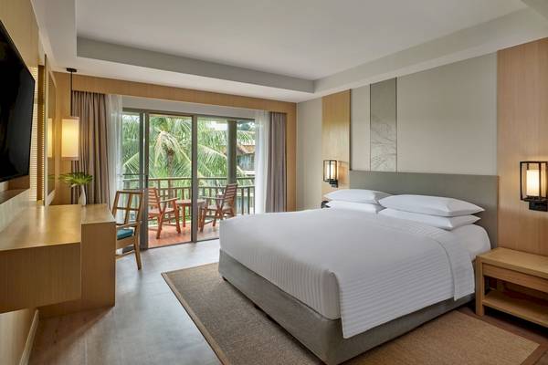 Innenansicht eines Zimmers im Phuket Marriott Resort & Spa Merlin Beach mit einem großen Bett, Balkon und Ausblick.