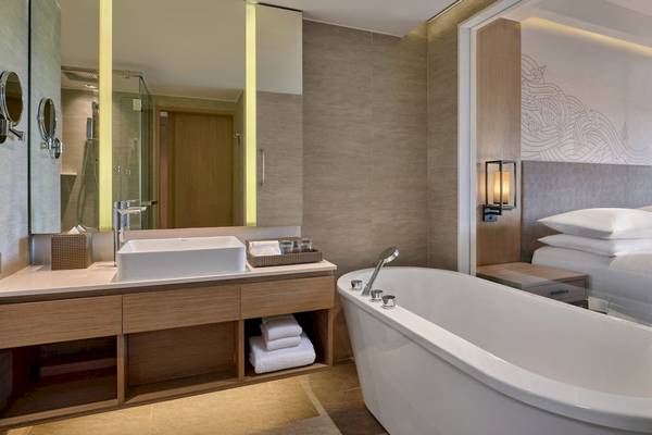 Badezimmer des Phuket Marriott Resort & Spa Merlin Beach mit Badewanne, Waschbecken und Spiegel.