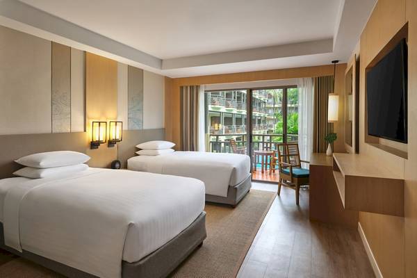 Zweibettzimmer im Phuket Marriott Resort & Spa Merlin Beach mit zwei Betten, einem Schreibtisch und einem Balkon mit Blick auf den Pool.