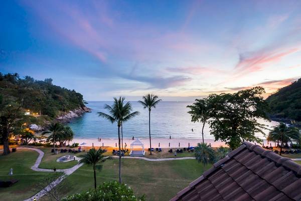 Abendstimmung am Strand des Phuket Marriott Resort & Spa Merlin Beach mit Blick auf das Meer, Bäume und eine Pavillon.