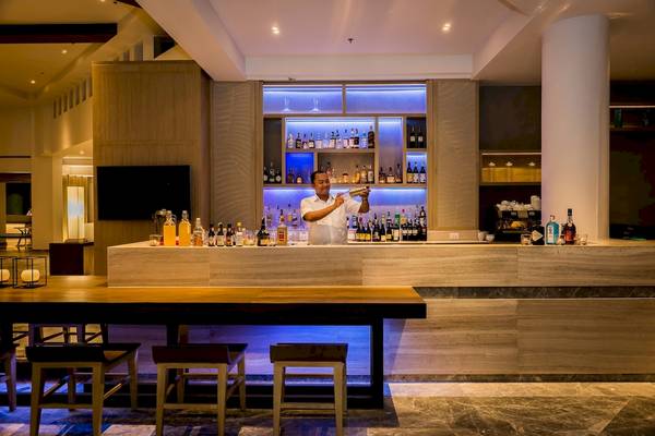 Cocktailbar im Phuket Marriott Resort & Spa Merlin Beach mit einem Barkeeper, der einen Cocktail zubereitet.