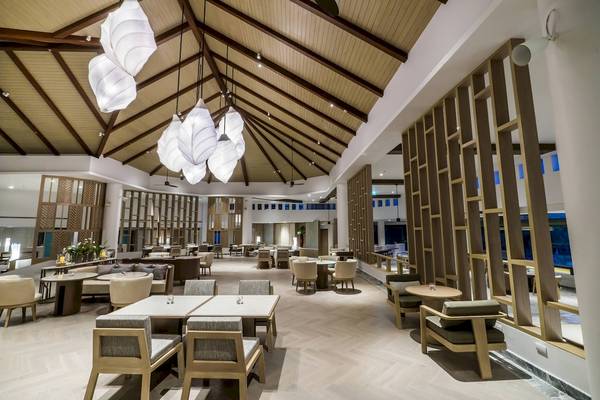 Innenansicht des Restaurants im Phuket Marriott Resort & Spa Merlin Beach mit Holztischen, Stühlen und Holzdecken.