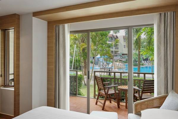 Bettzimmer mit Terrasse und Blick auf den Pool im Phuket Marriott Resort & Spa Merlin Beach.