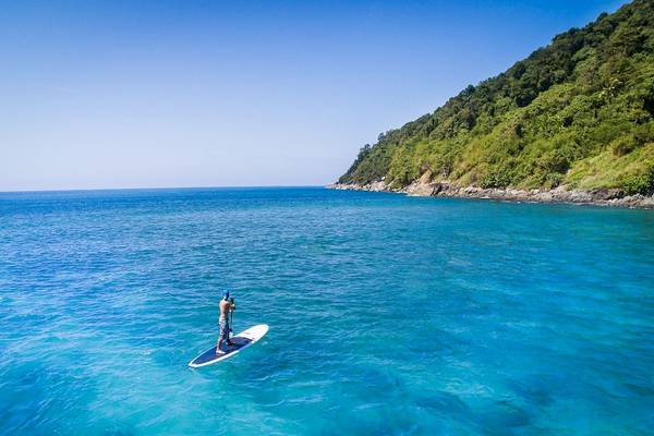 Ein Mann paddelt auf einem Sup-Board im blauen Meer in der Nähe des Phuket Marriott Resort & Spa Merlin Beach.