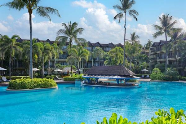 Außenpool des Phuket Marriott Resort & Spa Merlin Beach mit Palmen und Gebäuden im Hintergrund