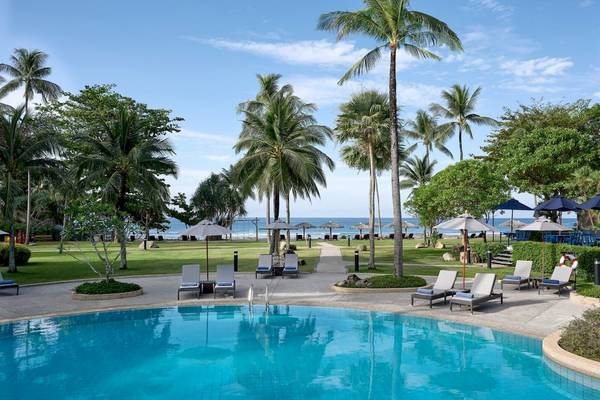Poolbereich des Phuket Marriott Resort & Spa am Merlin Beach mit Sonnenliegen und Sonnenschirmen.