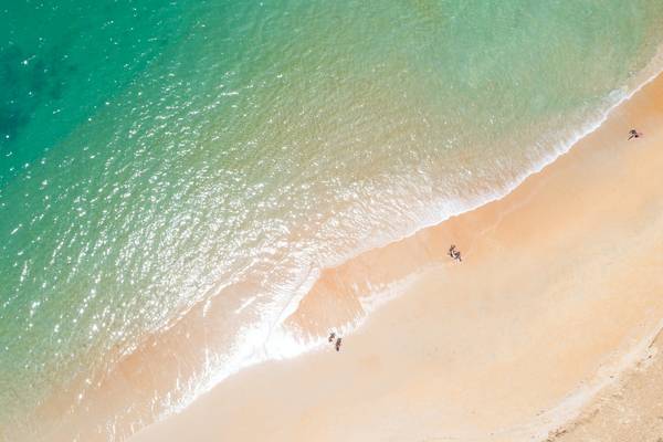 Oberflächenansicht eines Strandes mit Meer und Leuten, die auf dem Sand und im Wasser sind
