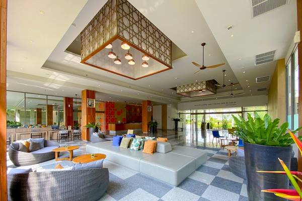 Lobby des X10 Khaolak Resorts mit gemustertem Boden, Sofas, Tischen und Pflanzen.