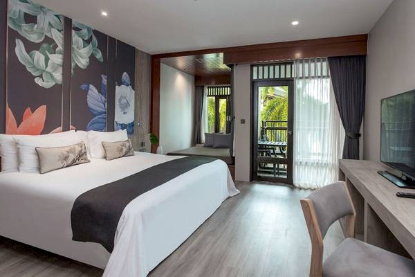 Schlafzimmer im La Flora Khao Lak Hotel mit Doppelbett, Fernseher und Balkonzugang
