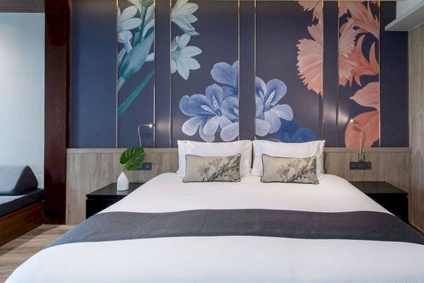 Schlafzimmer im La Flora Khao Lak Hotel mit blauen Blumentapeten und einem großen Bett.