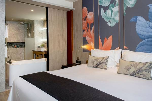 Hotelzimmer im La Flora Khao Lak mit Bett, Kissen, Badewanne und Badezimmerspiegel.