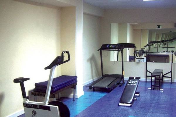 Fitnessraum im Argos Hotel mit Geräten und Spiegeln.