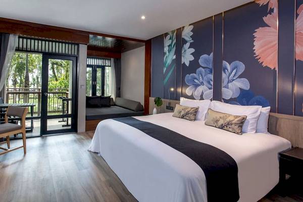Hotelzimmer im La Flora Khao Lak mit Doppelbett, Balkon und Sitzbereich.