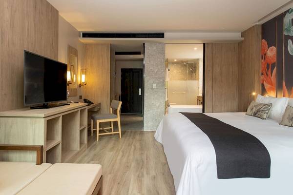 Ein modernes Hotelzimmer mit Fernseher, Schreibtisch und Bett im La Flora Khao Lak Hotel.