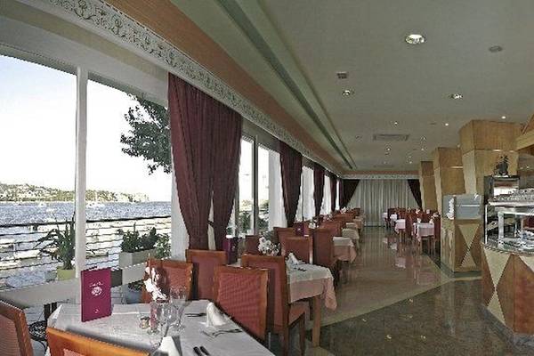 Innenansicht des Restaurants im Argos Hotel mit Blick auf den See und gedeckten Tischen.