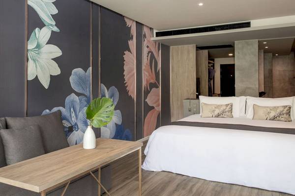 Schlafzimmer im La Flora Khao Lak Hotel mit floralen Wandtapeten und Doppelbett.