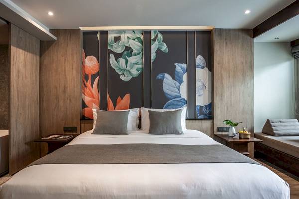 Schlafzimmer im La Flora Khao Lak Hotel mit Bett und Nachttischen.