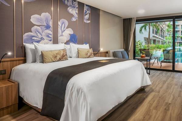 Schlafzimmer im La Flora Khao Lak Hotel mit großem Bett, blauen Blumenmustern an der Wand und Terrassenzugang.