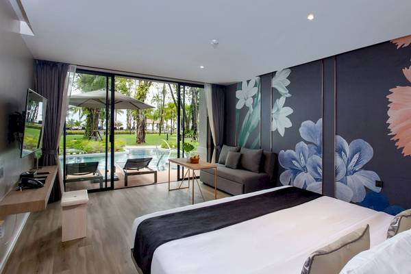 Innenansicht eines Hotelzimmers von La Flora Khao Lak mit Blick auf einen Pool und Garten.