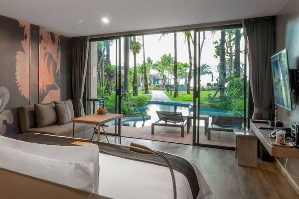 Ein modernes Hotelzimmer von La Flora Khao Lak mit Blick auf einen Swimmingpool.