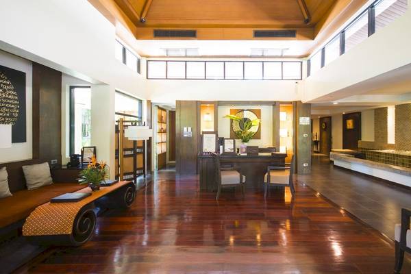 Empfangsbereich des La Flora Khao Lak Hotels mit Holzboden, Sitzmöbeln und Pflanzen.