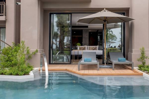 Außenbereich des La Flora Khao Lak mit Pool, Liegen und Sonnenschirm.