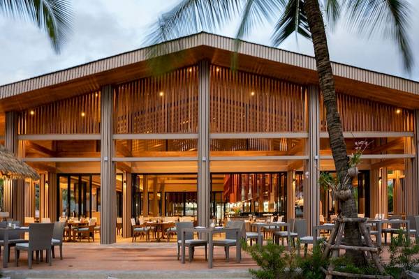 Außenbereich des La Flora Khao Lak Hotels mit modernen Holzarchitekturen, Tischen und Stühlen.