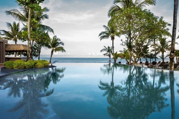 Ein großer Pool im Freien am Strand des La Flora Khao Lak Hotels, umgeben von Palmen und Blick auf das Meer.