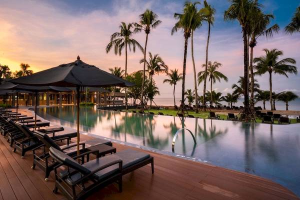 La Flora Khao Lak Hotelpool mit Sonnenschirmen und Lounge-Sesseln bei Sonnenuntergang