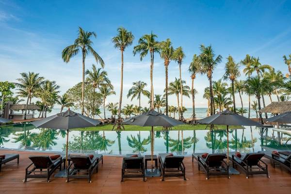 Pool-Lounge-Bereich des La Flora Khao Lak Hotels mit Sonnenliegen und Schirmen vor Palmen