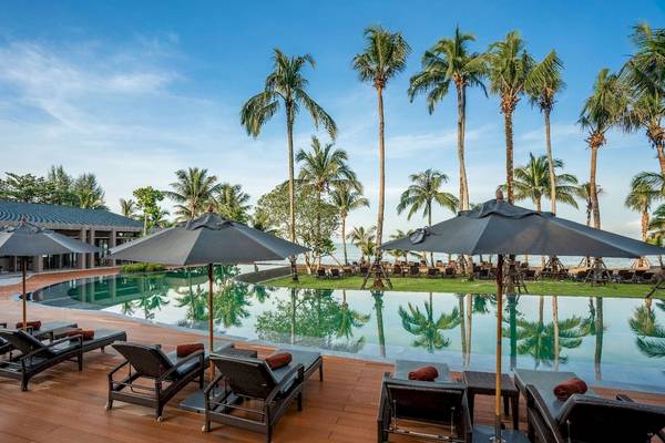 Außenbereich des La Flora Khao Lak Hotels mit Loungestühlen, Sonnenschirmen und einem Pool