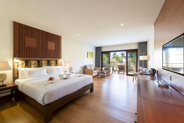 Innenansicht eines Hotelzimmers im The Haven Khao Lak mit Bett, Wohnzimmer und Terrasse.