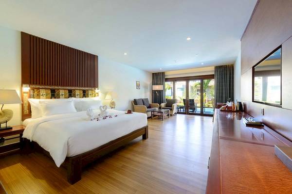 Innenansicht eines Hotelzimmers von The Haven Khao Lak mit einem großen Bett, Rosenblättern und einer Terrasse.