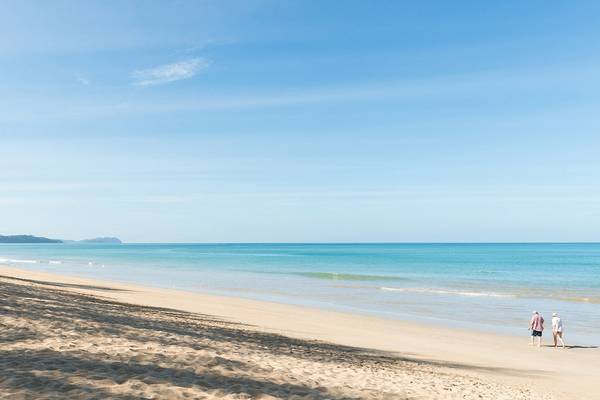Zwei Wanderer auf einem Strand mit blauem Himmel und kristallklarem Wasser vor dem Haven Khao Lak