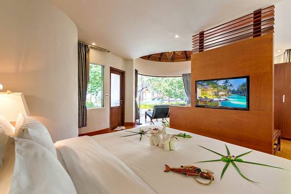 Hotelzimmer von The Haven Khao Lak mit einem Bett, Fernseher und Blick auf den Pool.