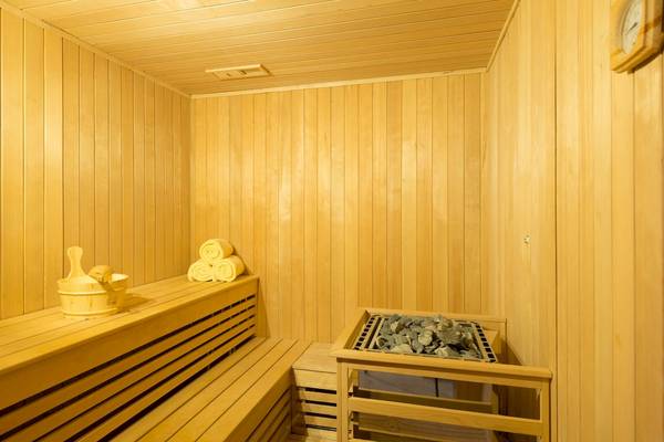 Saunaraum im Haven Khao Lak Hotel mit Holzwänden, Handtüchern und einem Steinkorb.