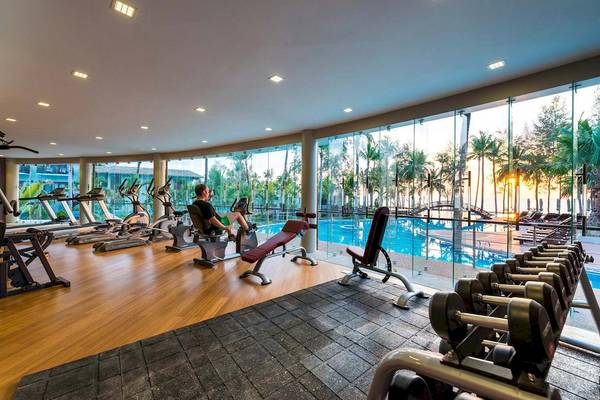 Fitnessstudio im The Haven Khao Lak mit Blick auf den Pool und die Palmen