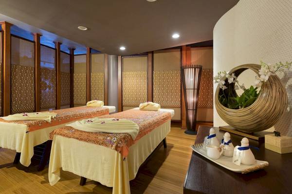 Massageraum im The Haven Khao Lak mit zwei Massagetischen und dekorativen Elementen.