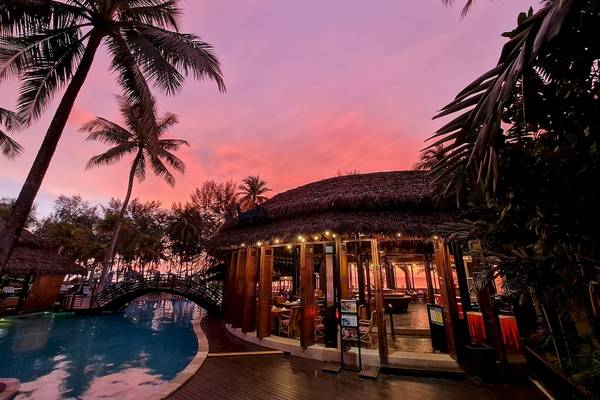 Abendlicher Blick auf das The Haven Khao Lak Hotel mit Swimmingpool und tropischen Bäumen.