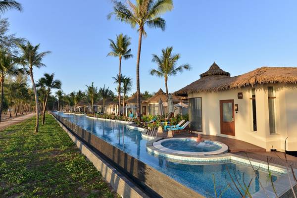 Der Außenpool und Bungalows im The Haven Khao Lak Hotel mit tropischer Vegetation und Sonnenschirmen.