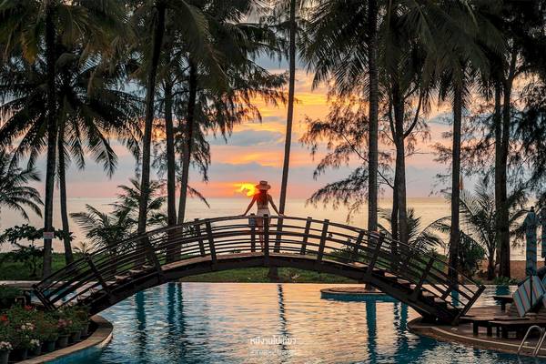 Sonnenuntergang am Pool im Haven Khao Lak mit einer Frau auf einer Brücke.