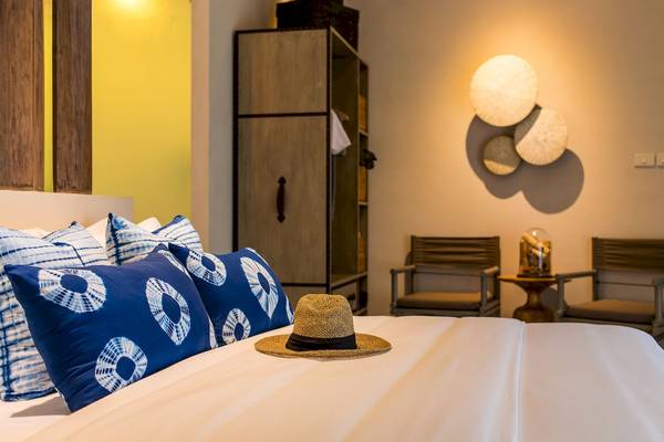 Ein Hotelzimmer von Bangsak Village mit einem Bett, Hut, Stühle und Dekor an der Wand.