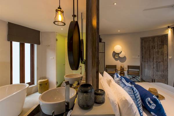Innenansicht des Schlafzimmers im Bangsak Village Hotel mit Bett, Spiegeln und Deko.