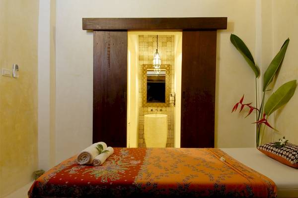 Innenansicht des Bangsak Village Hotels mit Bett, Handtüchern und Pflanze.